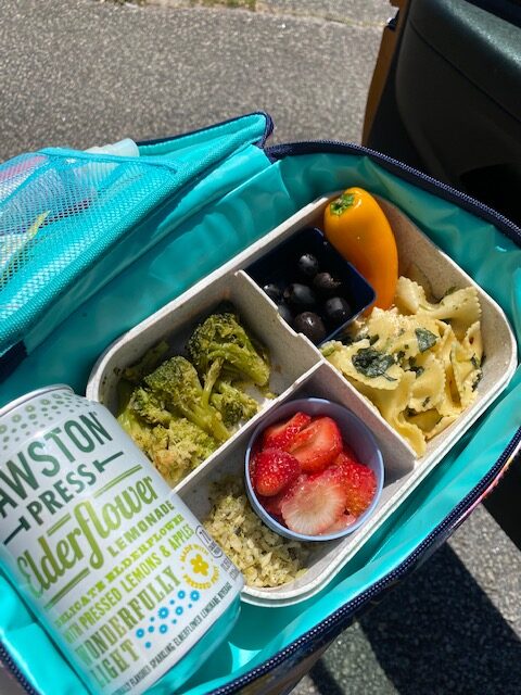 Lunch with pasta, vegetables, fruit, and a canned drink. 